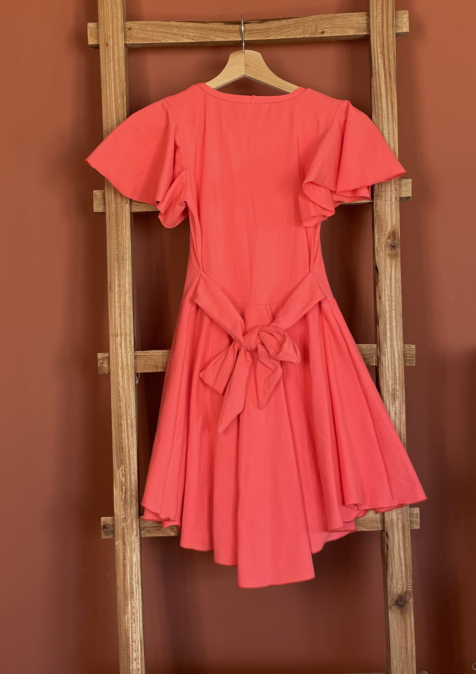 hooglaag-jurk-met-cirkel-mouwen-spicy-coral-met-strik-achterkant-scaled-e1709673995527.jpg