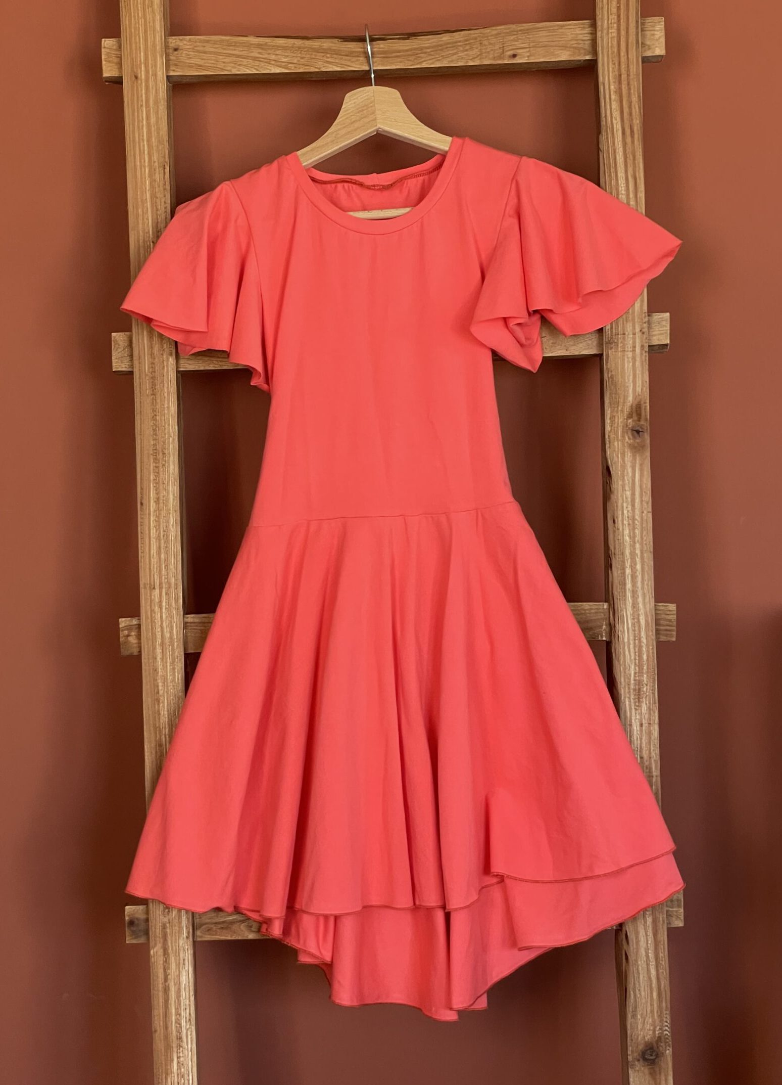 hooglaag-jurk-met-cirkel-mouwen-spicy-coral-met-strik-voorkant-scaled-e1709674023528.jpg